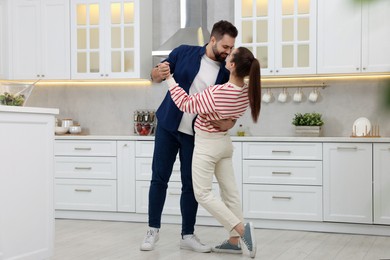 Photo of Happy lovely couple dancing together in kitchen