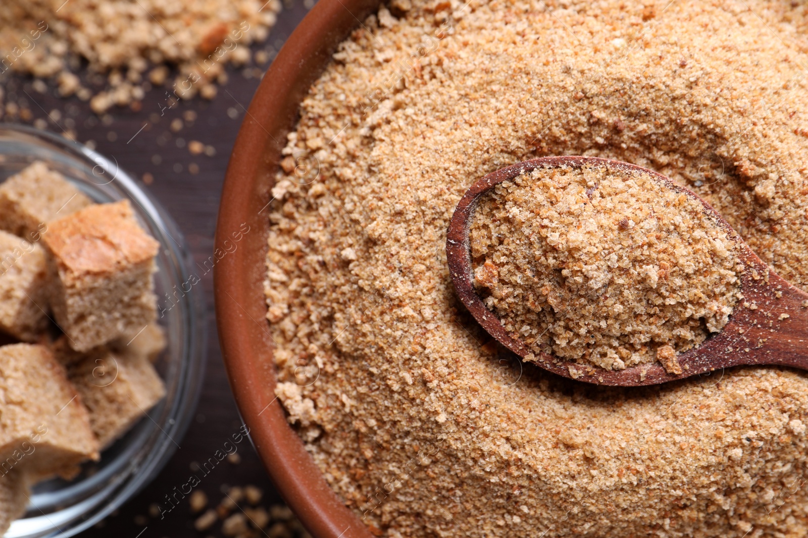 Photo of Fresh breadcrumbs and spoon on wooden table, flat lay