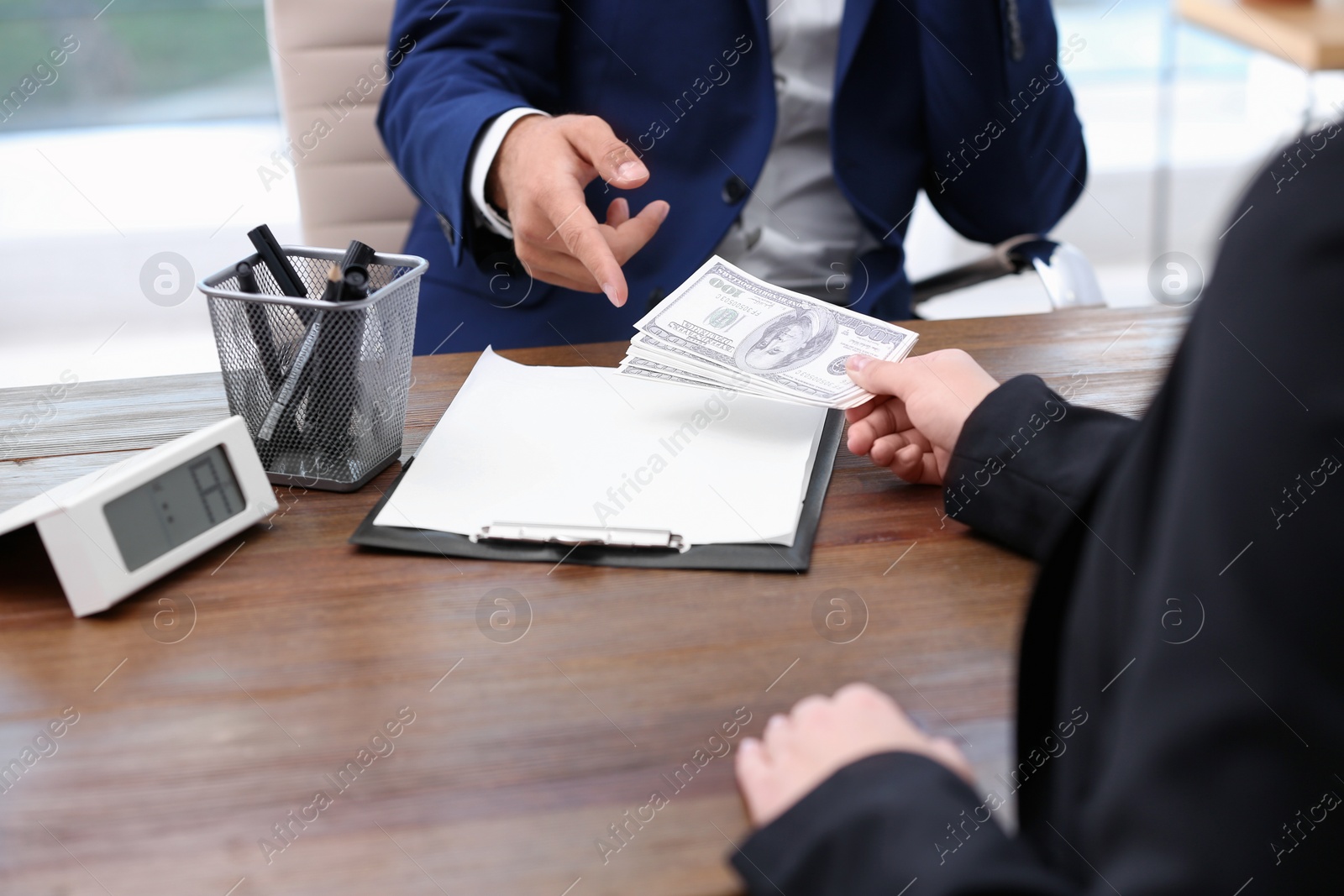 Photo of Woman giving bribe money to man at table, closeup