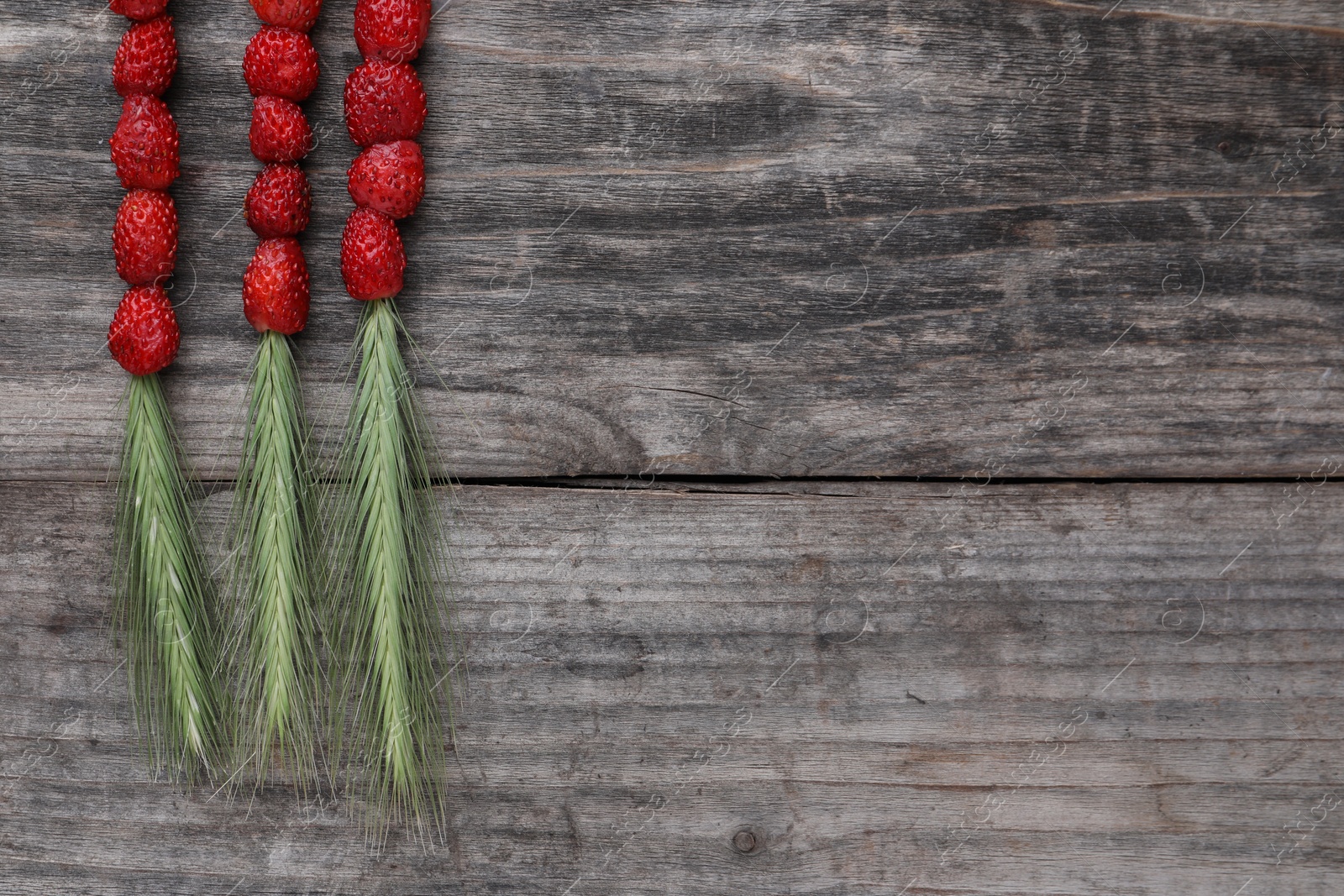 Photo of Grass stems with wild strawberries on wooden table, flat lay. Space for text