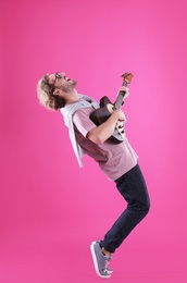 Young man playing electric guitar on color background