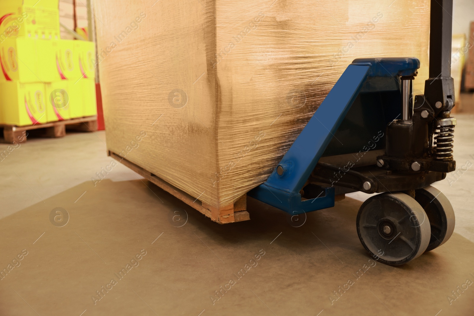 Image of Manual forklift with wrapped pallets in warehouse, closeup. Logistics concept