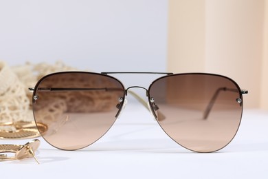 Photo of New stylish elegant sunglasses on white table, closeup