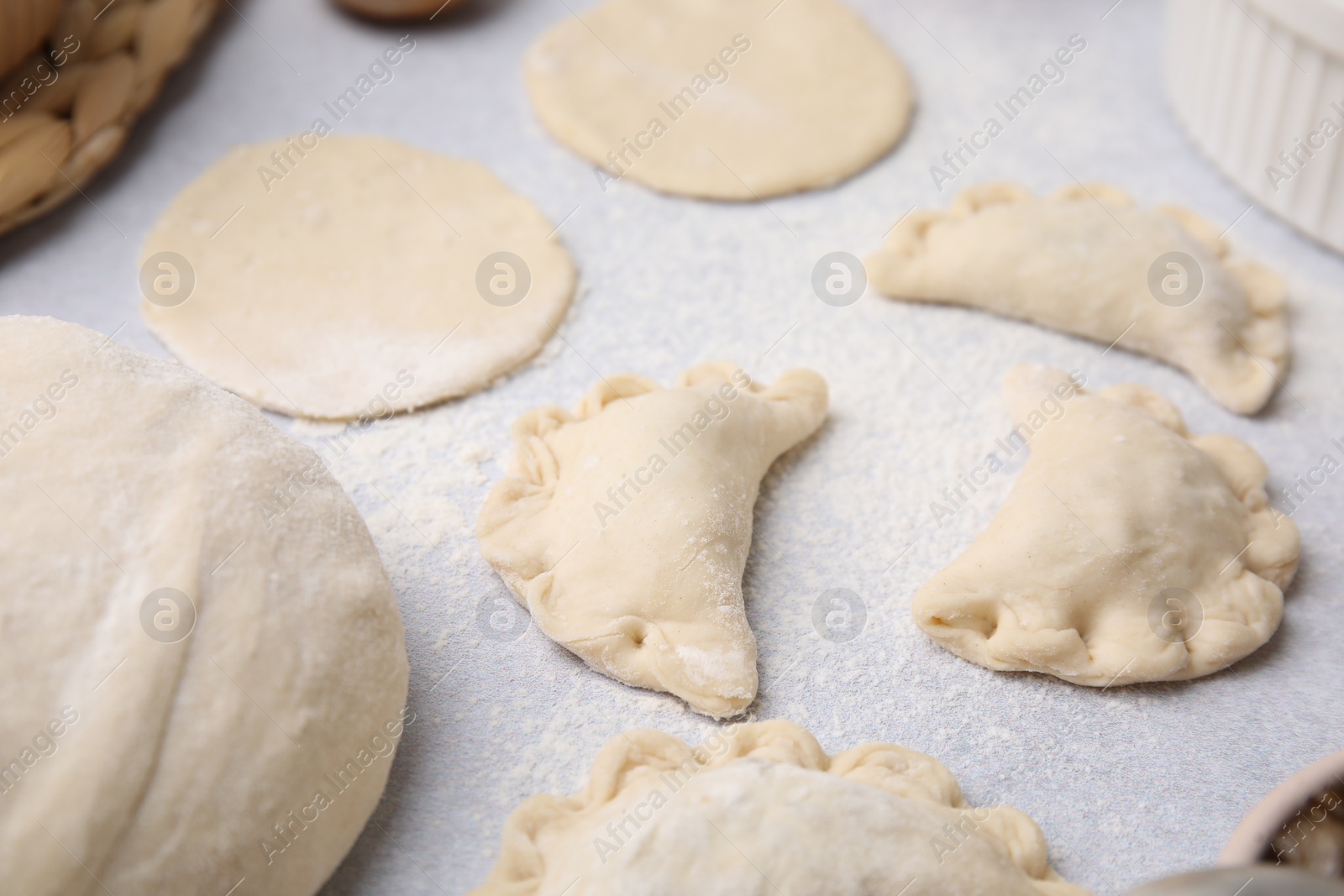 Photo of Process of making dumplings (varenyky) with mushrooms. Raw dough with filling on white table, closeup