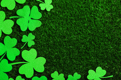 Photo of Flat lay composition with clover leaves on green grass, space for text. St. Patrick's Day celebration