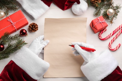 Santa Claus writing letter at white wooden table, top view. Christmas celebration