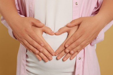 Photo of Man hugging his pregnant wife on light brown background, closeup