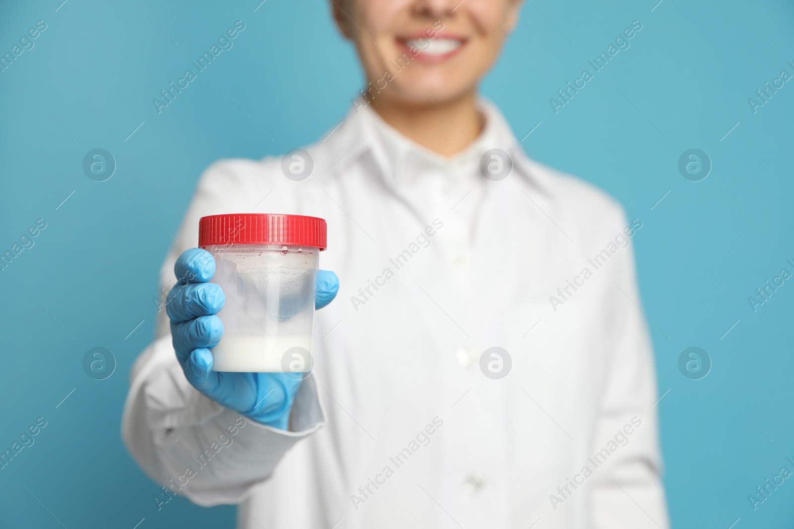 Photo of Scientist holding container with sperm on turquoise background, closeup. Space for text