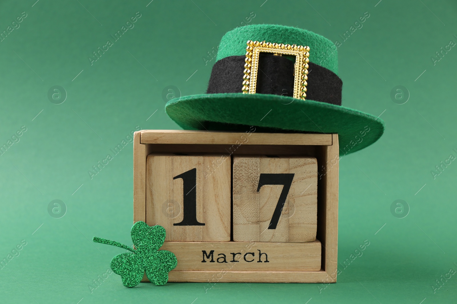 Photo of St. Patrick's day - 17th of March. Block calendar, leprechaun hat and decorative clover leaf on green background