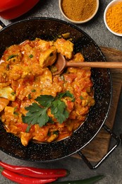 Photo of Delicious chicken curry and spices on grey table, flat lay