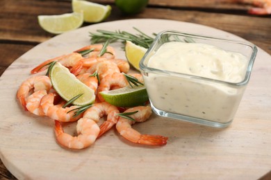 Photo of Delicious shrimp cocktail and tartar sauce on board, closeup