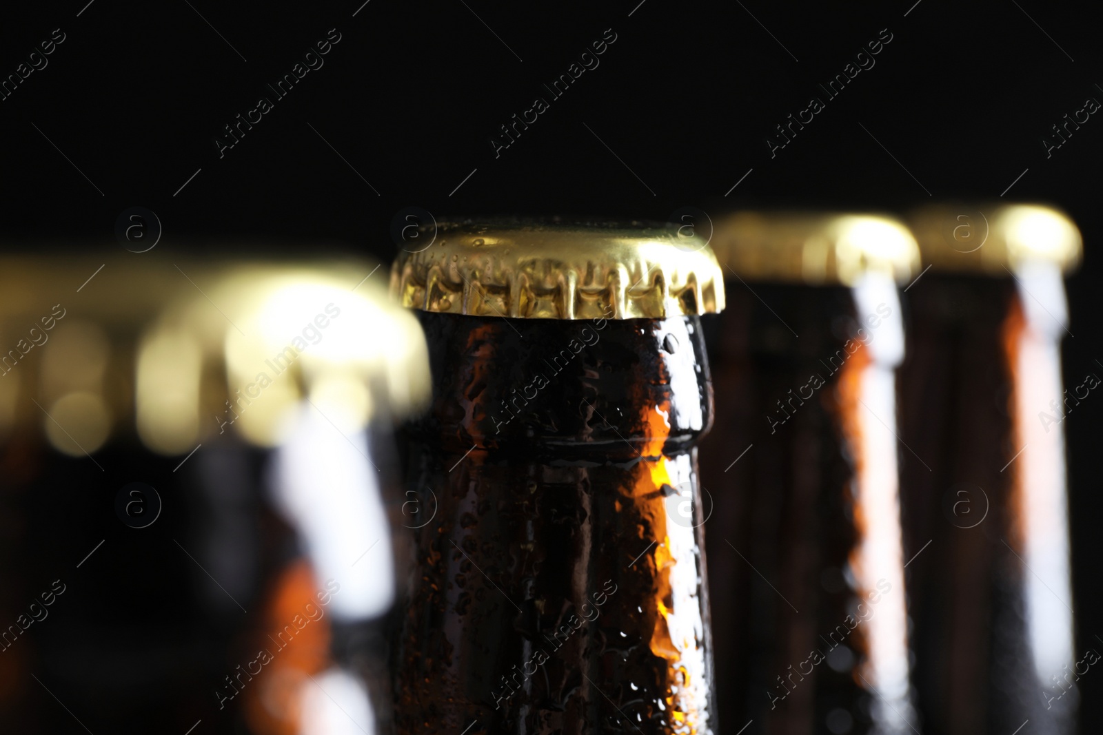 Photo of Many bottles of beer on dark background, closeup view