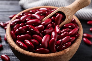 Photo of Raw red kidney beans in wooden bowl and scoop on table, closeup