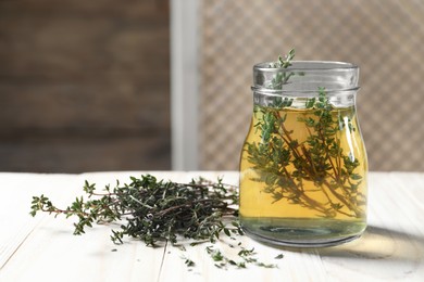 Aromatic herbal tea with thyme on white wooden table indoors, space for text