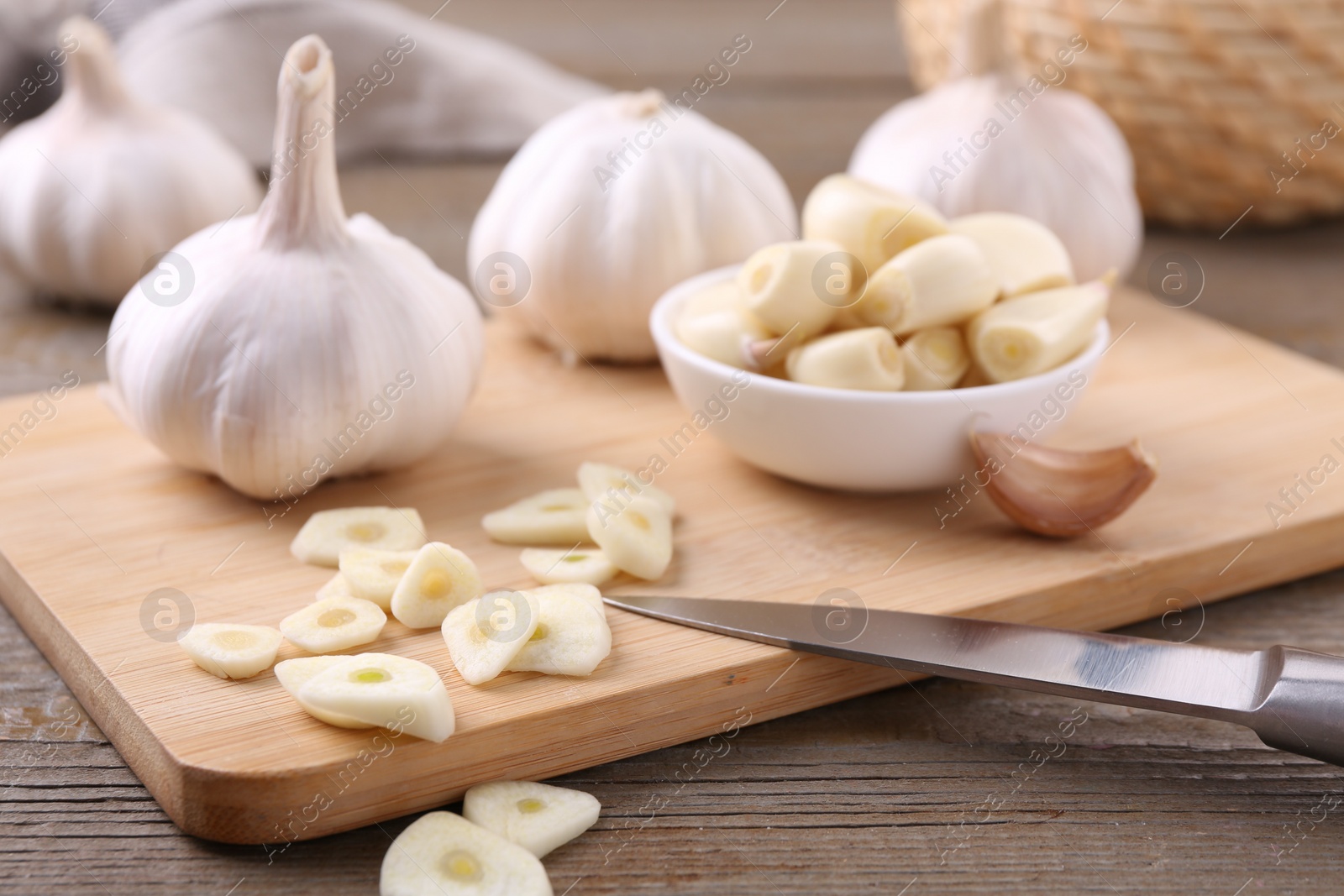 Photo of Aromatic cut garlic, cloves and bulbs on wooden table, closeup