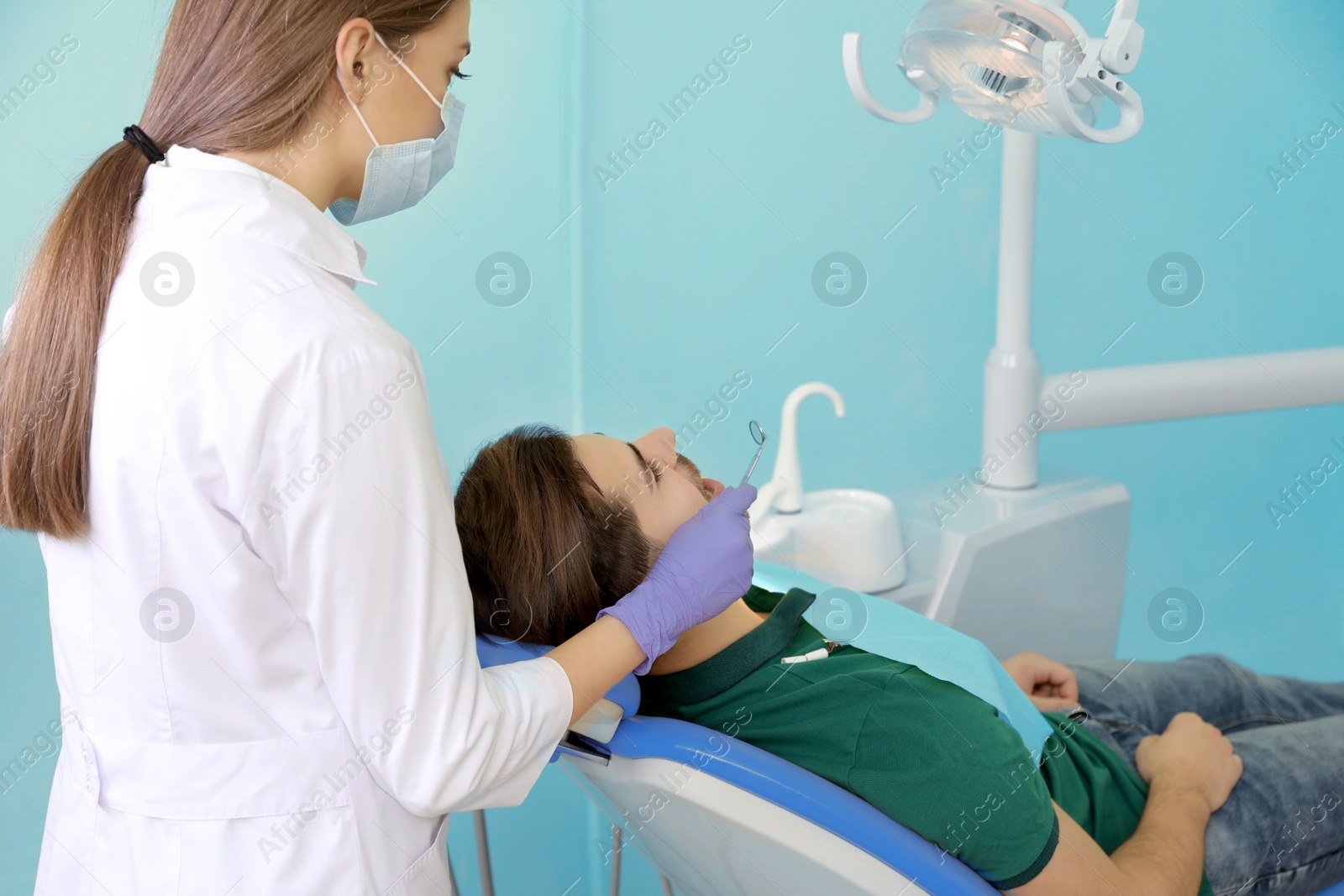 Photo of Professional dentist working with patient in modern clinic