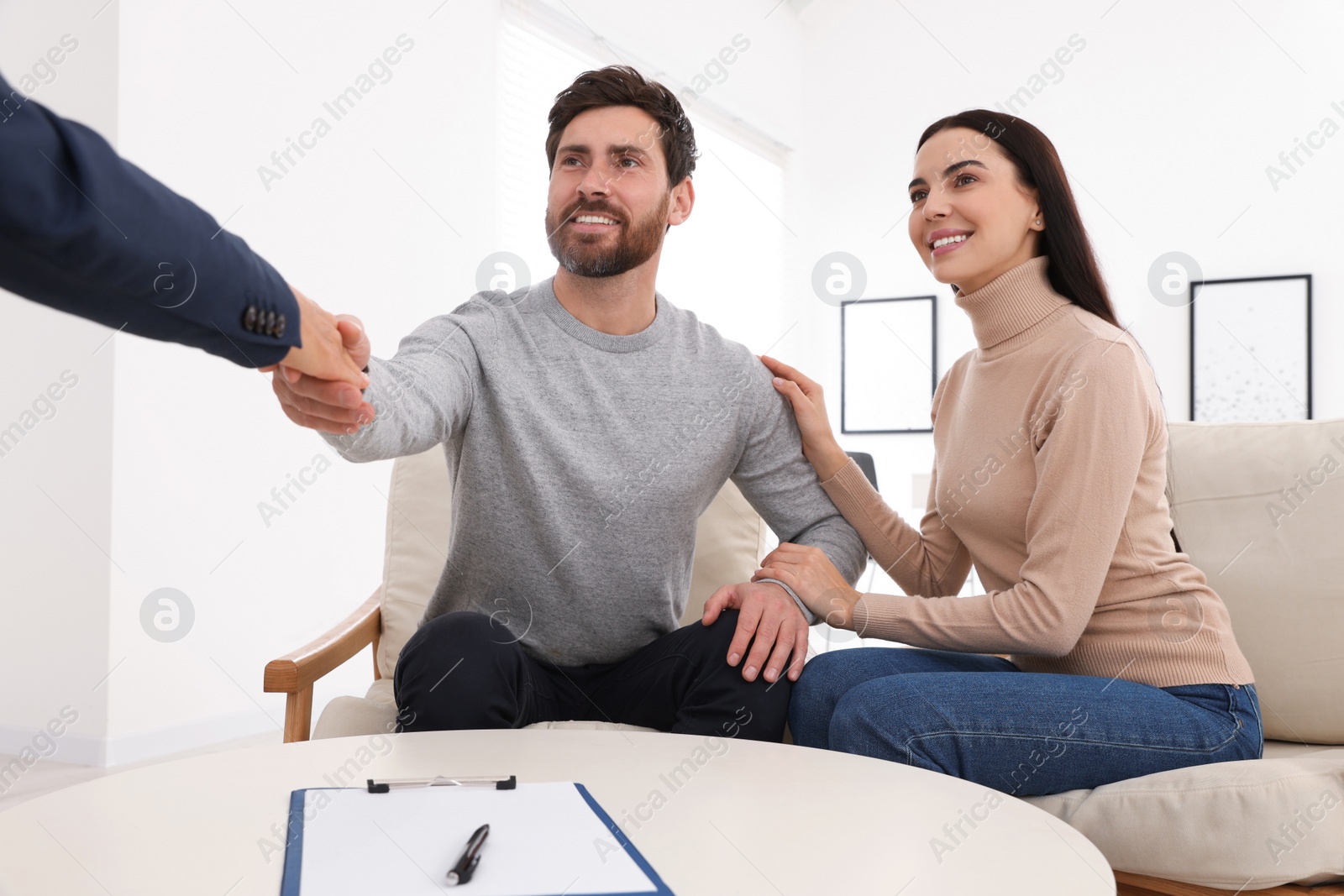 Photo of Real estate agent shaking hands with client at table in office, closeup