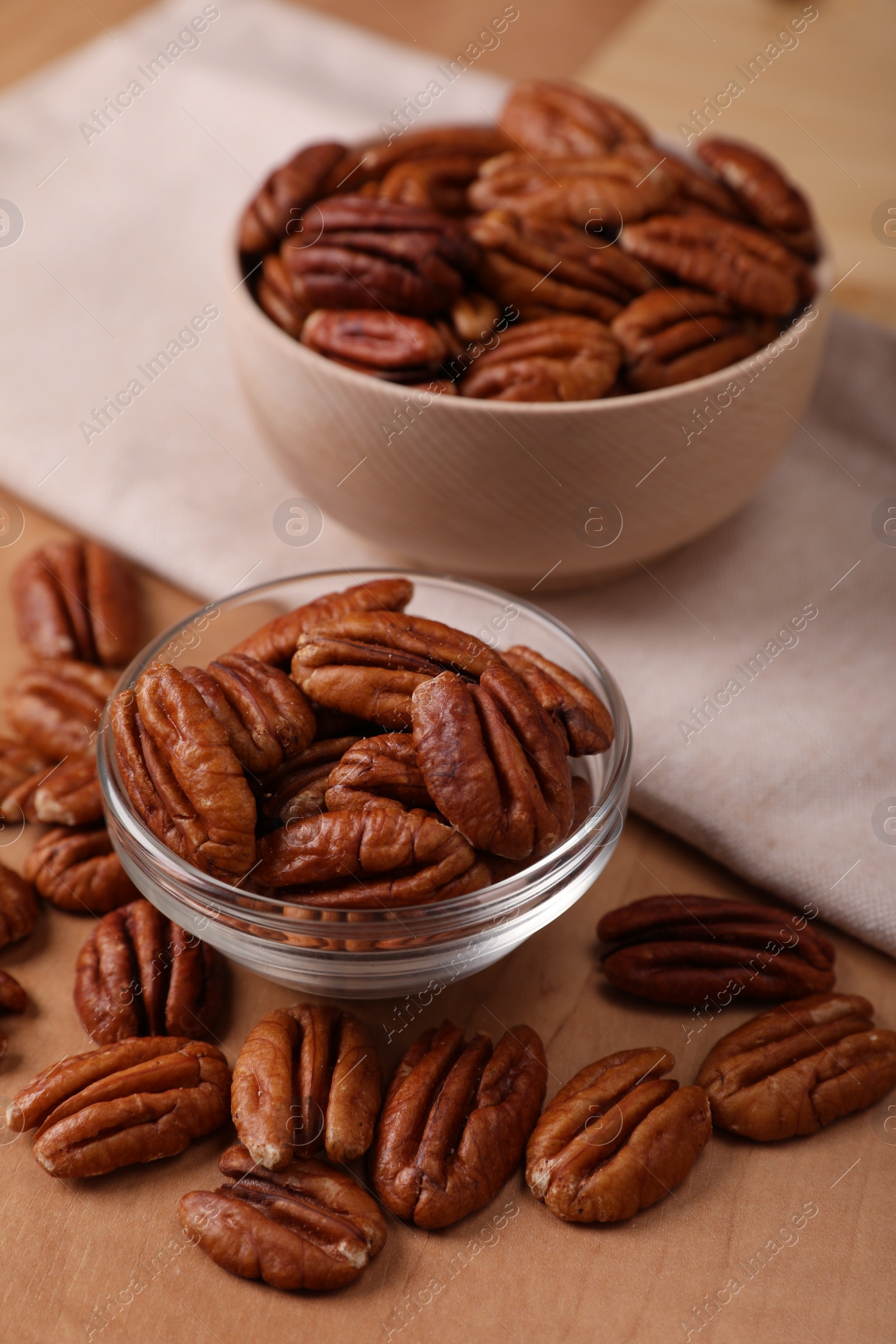 Photo of Bowls and tasty pecan nuts on wooden table