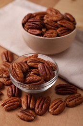 Bowls and tasty pecan nuts on wooden table