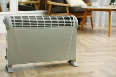 Photo of Modern electric convection heater on floor at home