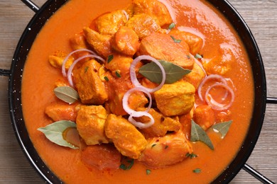 Photo of Delicious chicken curry in pan on wooden table, top view