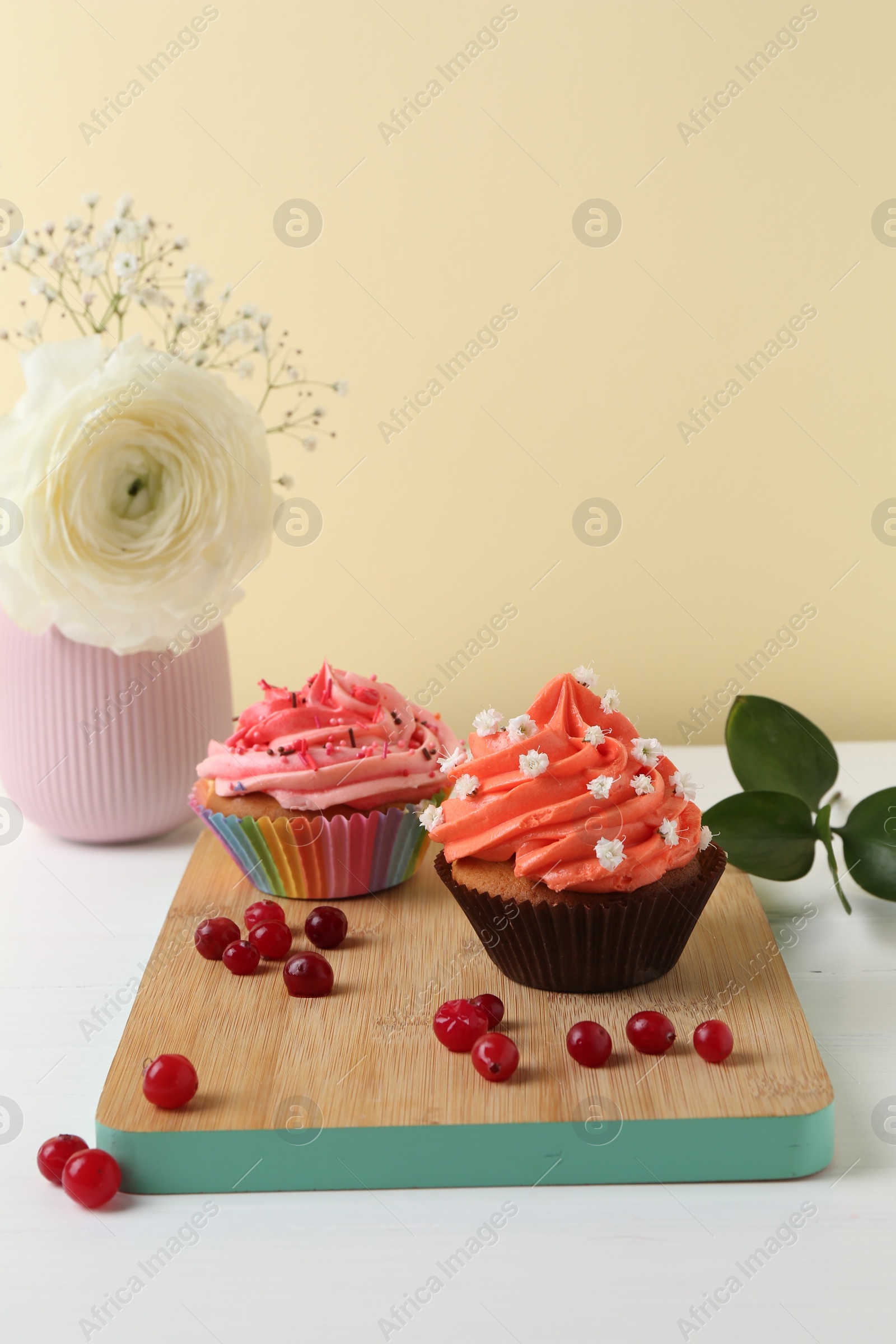 Photo of Delicious cupcake with bright cream and flowers on white wooden table