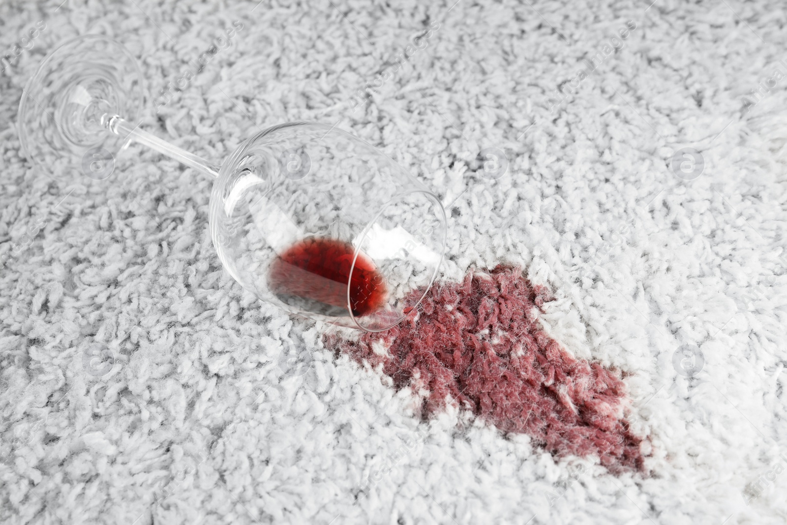 Photo of Overturned glass and spilled exquisite red wine on soft carpet