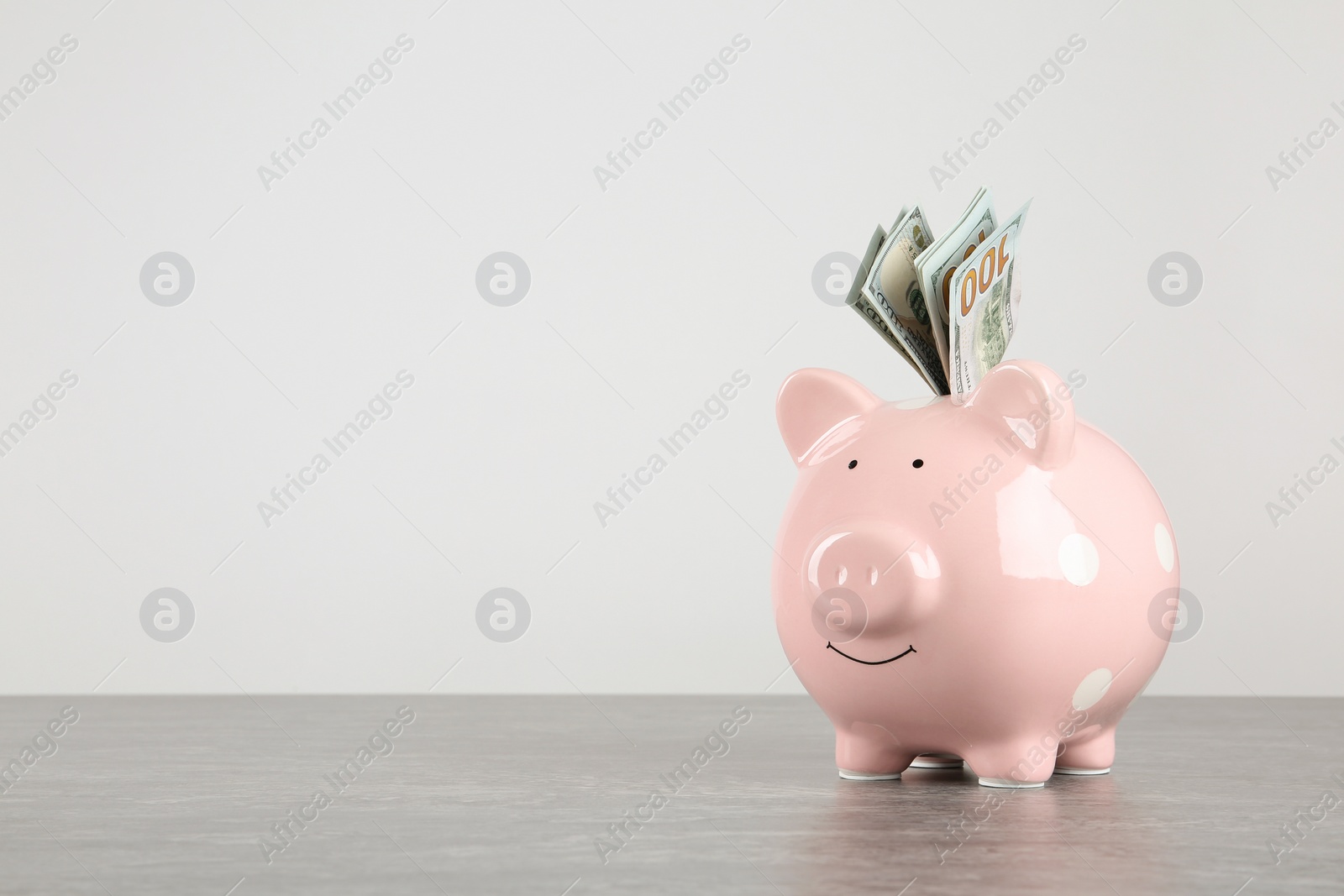 Photo of Piggy bank with dollar banknotes on table against white background. Space for text