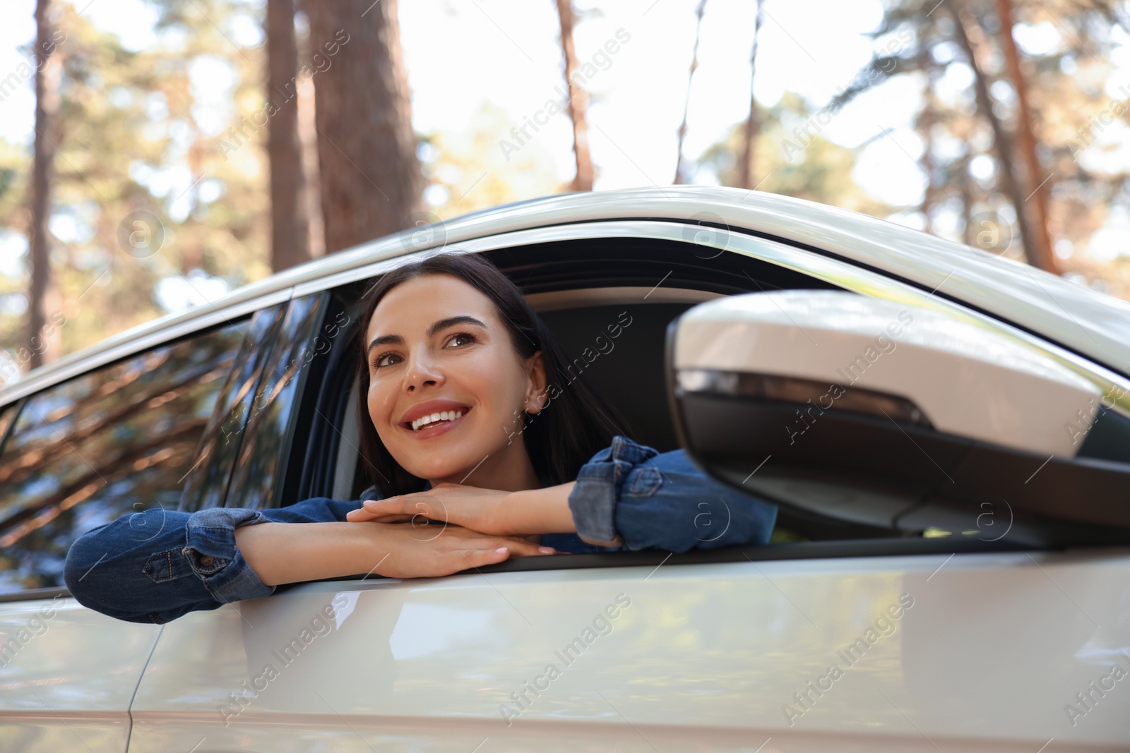 Photo of Happy young woman looking out of car window, view from outside. Enjoying trip