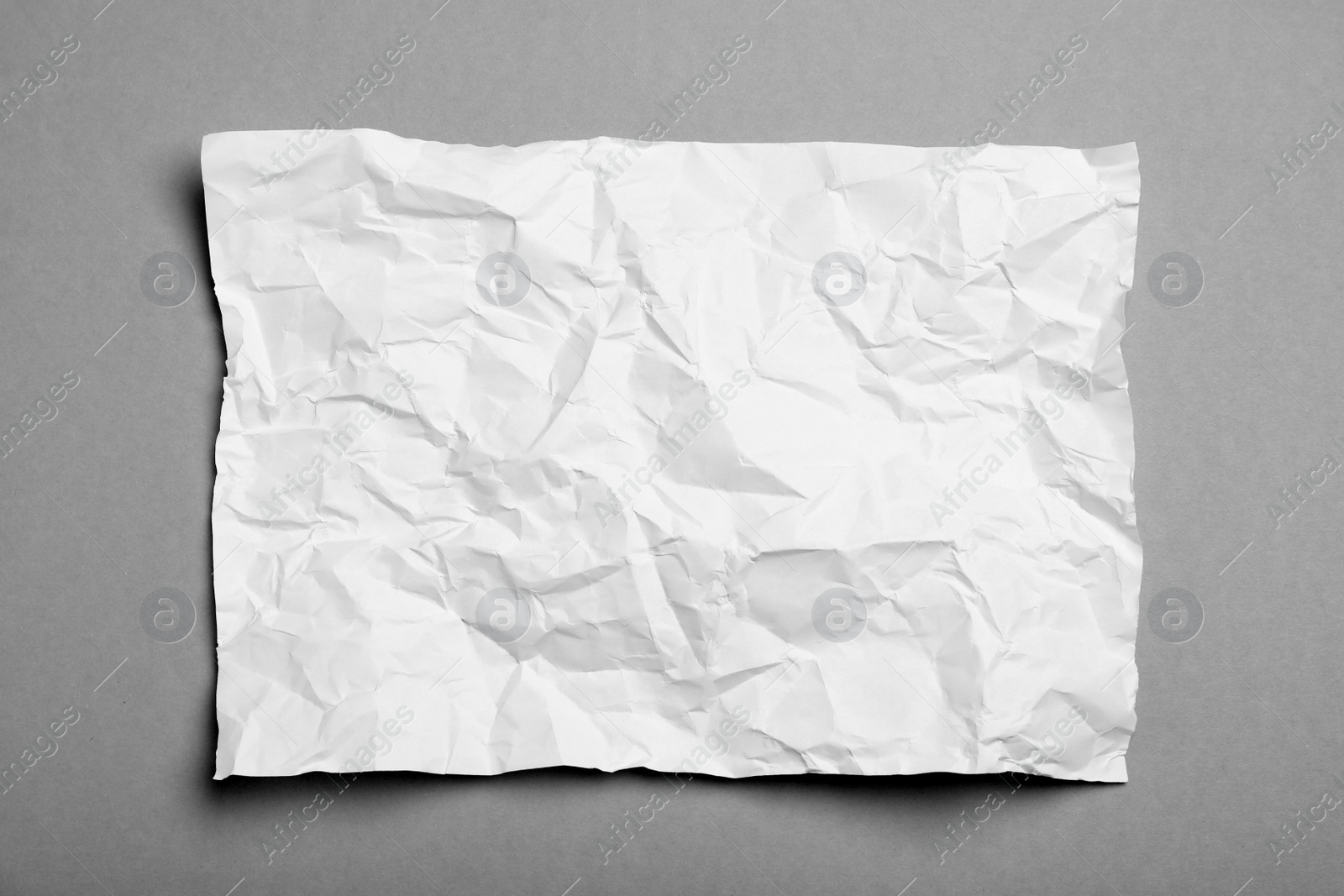 Photo of Sheet of white crumpled paper on grey background, top view