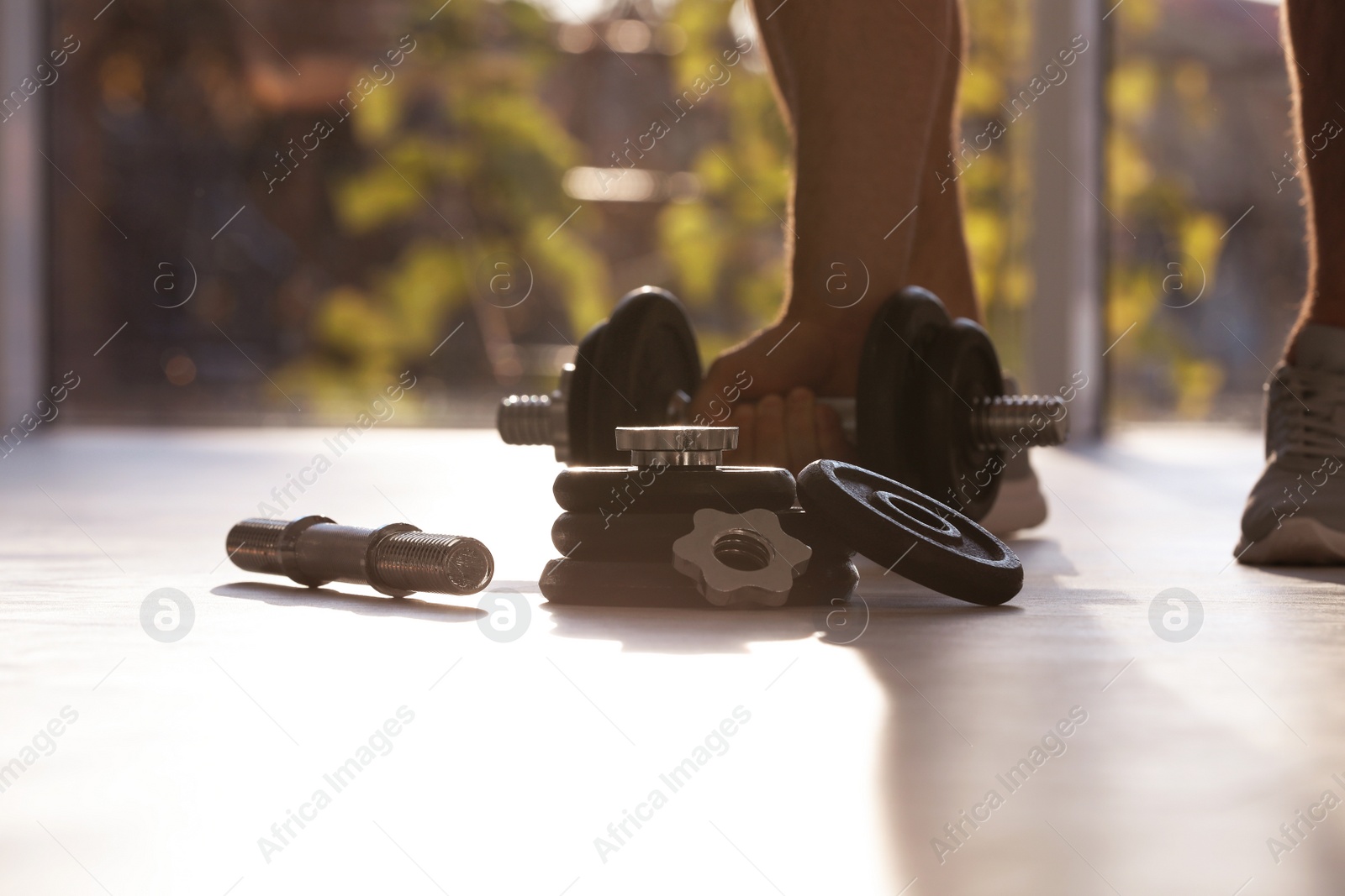 Photo of Male athlete with adjustable dumbbells indoors. Sports equipment