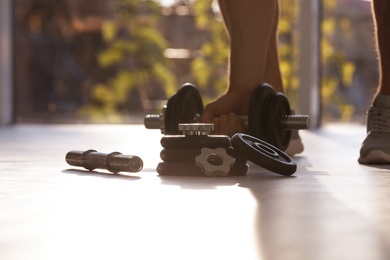 Photo of Male athlete with adjustable dumbbells indoors. Sports equipment