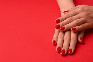Photo of Woman with gel polish on nails on red background, closeup. Space for text