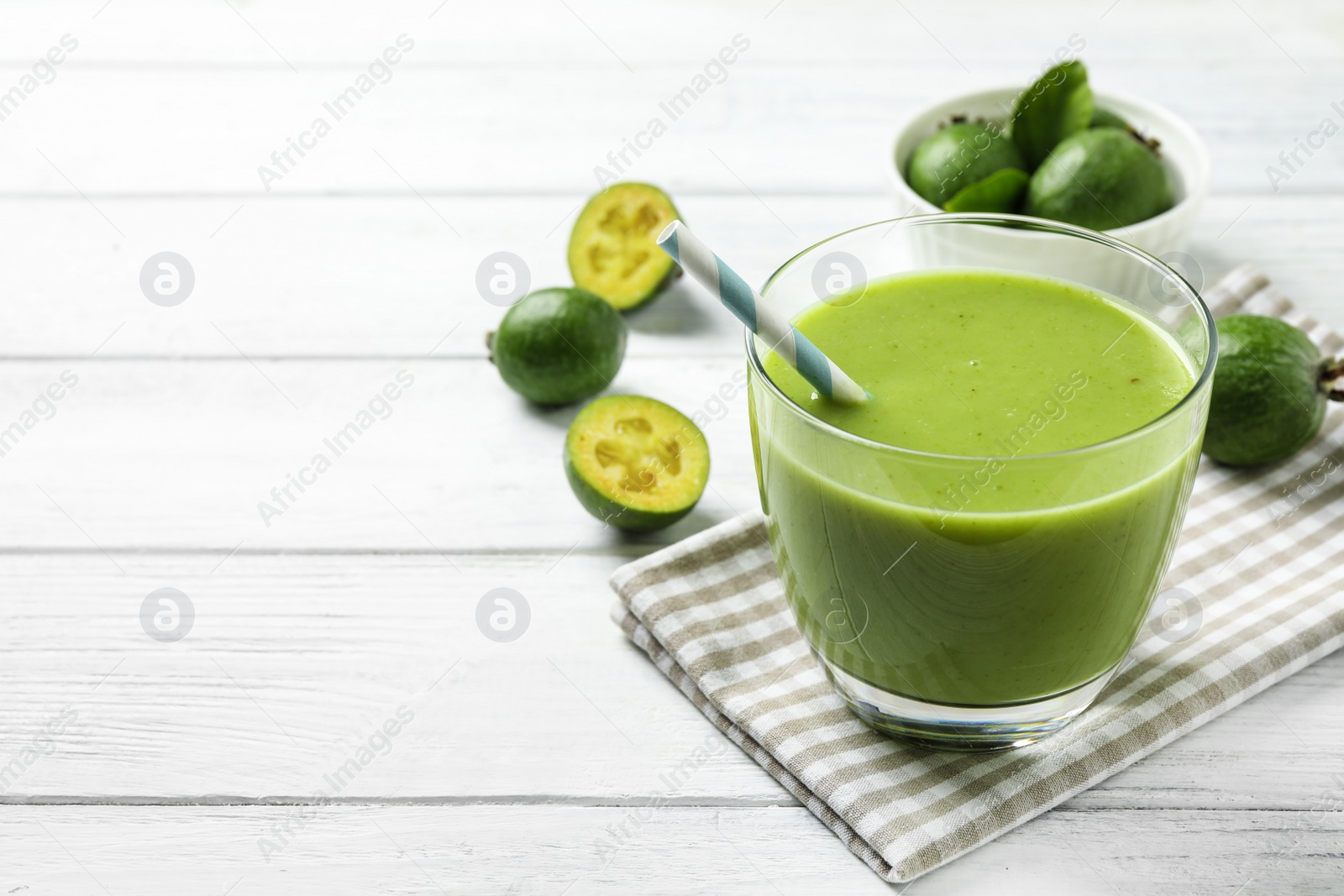 Photo of Fresh feijoa smoothie in glass on white wooden table. Space for text