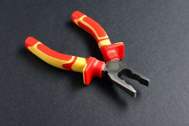 Photo of Combination pliers on black background, closeup view