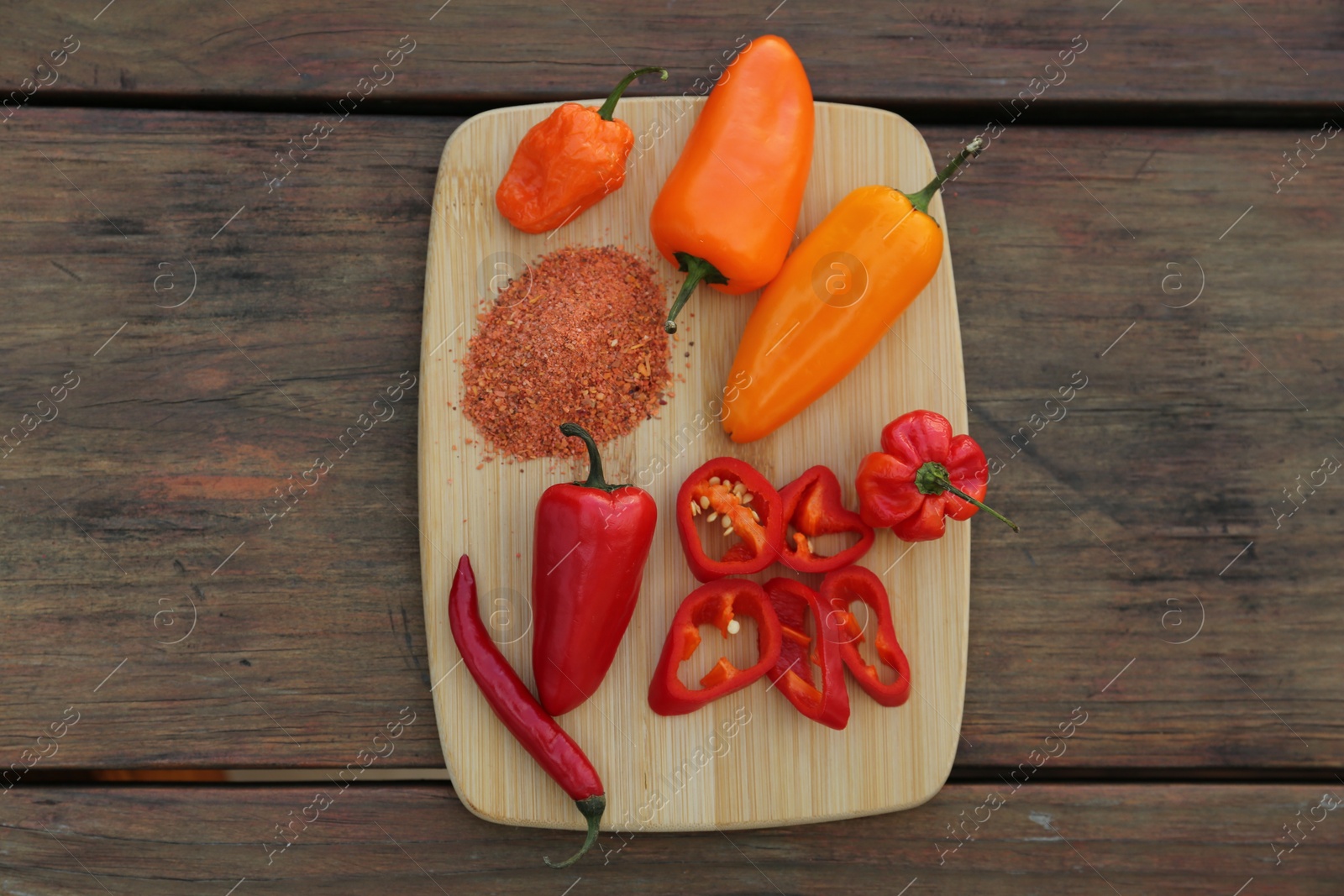 Photo of Many different peppers and spoon with spice on wooden table, top view