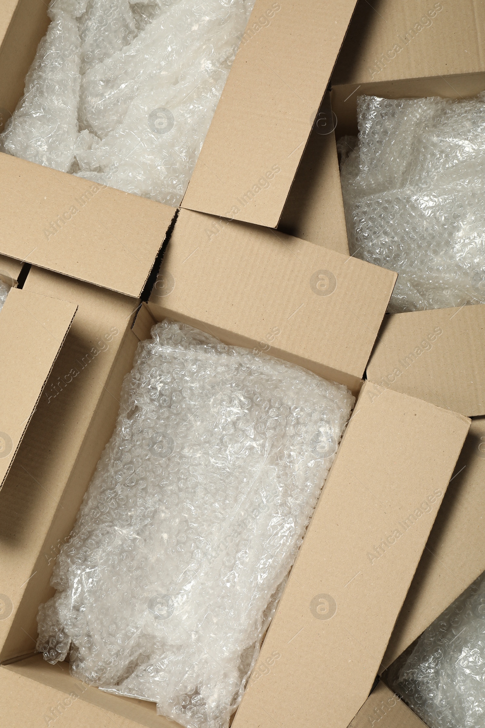 Photo of Many open cardboard boxes with bubble wrap as background, top view