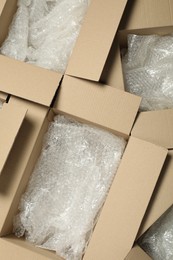 Photo of Many open cardboard boxes with bubble wrap as background, top view