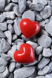Photo of Red decorative hearts on grey stones, top view