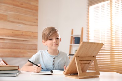 Boy doing homework with tablet at table indoors