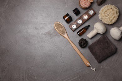 Flat lay composition with different spa products and burning candles on grey textured table. Space for text