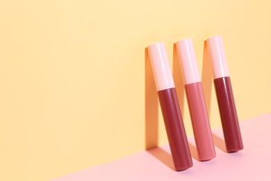 Photo of Different lip glosses on color background, space for text