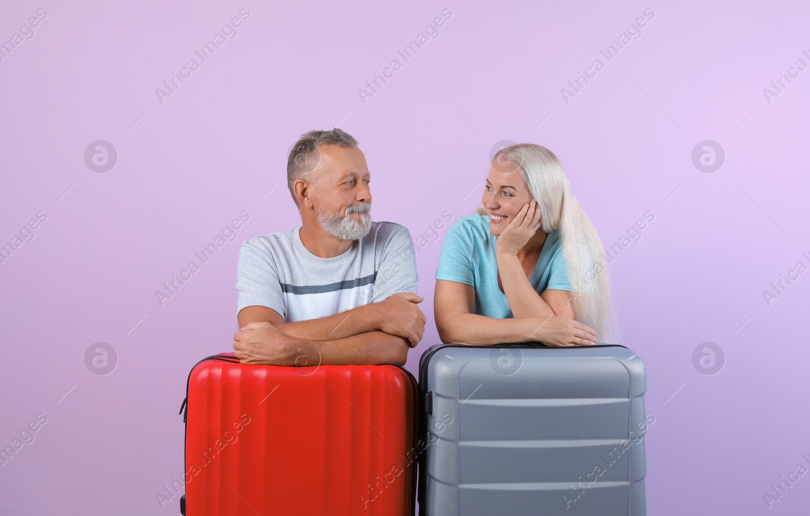 Photo of Senior couple with suitcases on color background. Vacation travel