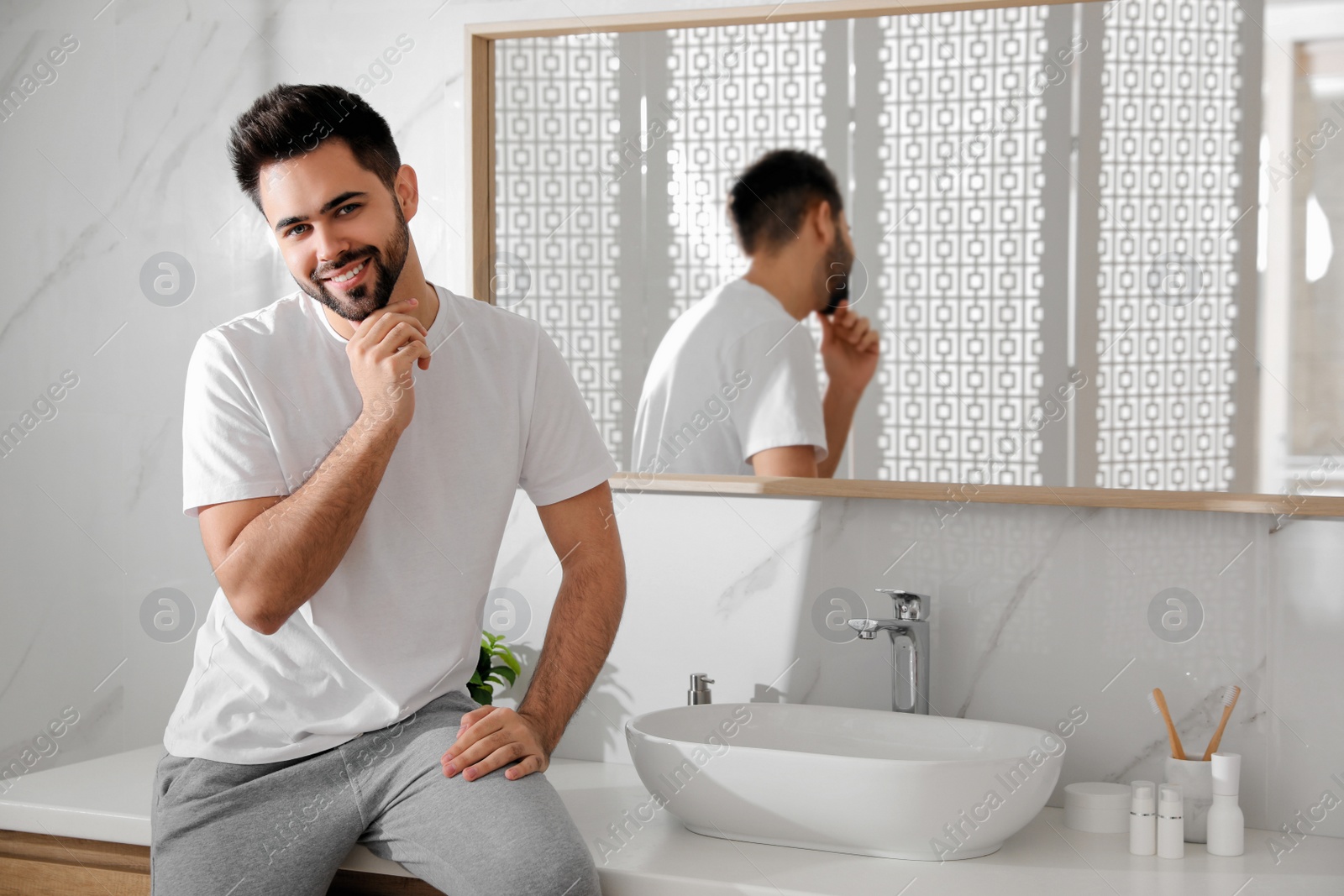 Photo of Handsome young man after shaving in bathroom, space for text