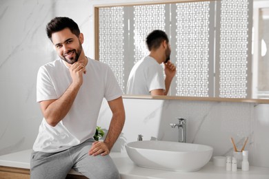 Handsome young man after shaving in bathroom, space for text