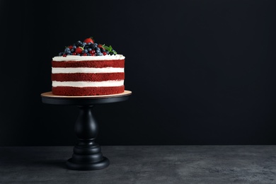 Photo of Stand with delicious homemade red velvet cake and space for text on black background