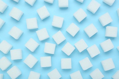 Photo of White sugar cubes on light blue background, top view