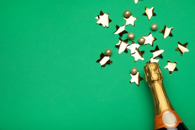 Photo of Flat lay composition with confetti and bottle of champagne on green background. Space for text