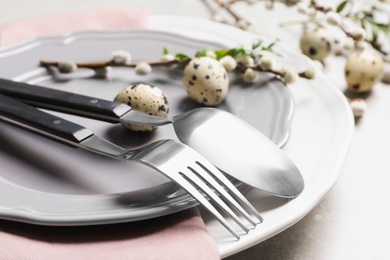 Festive Easter table setting with quail eggs on color background, closeup