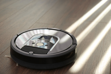 Modern robotic vacuum cleaner on wooden floor